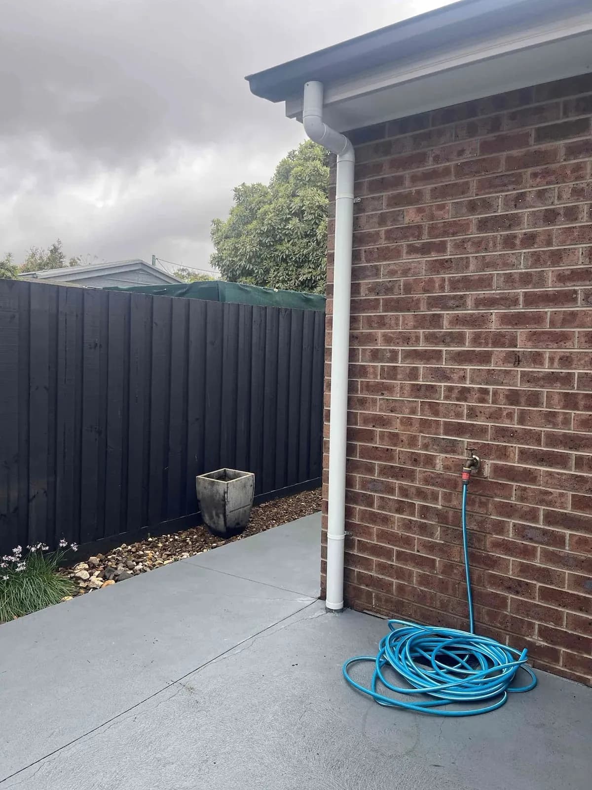 Outside tap and hose beside a new downpipe