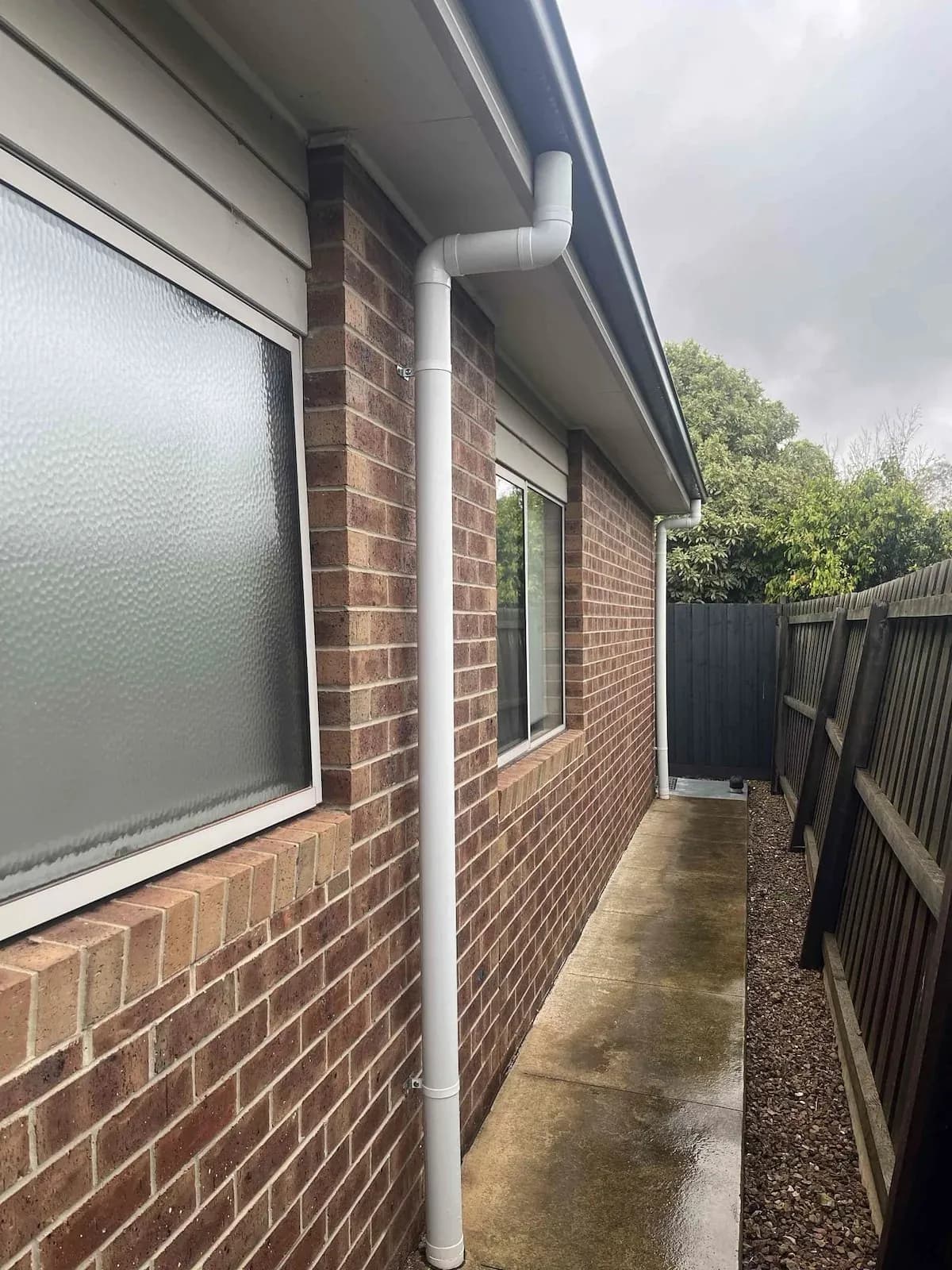 New PVC downpipe along the side of a brick house
