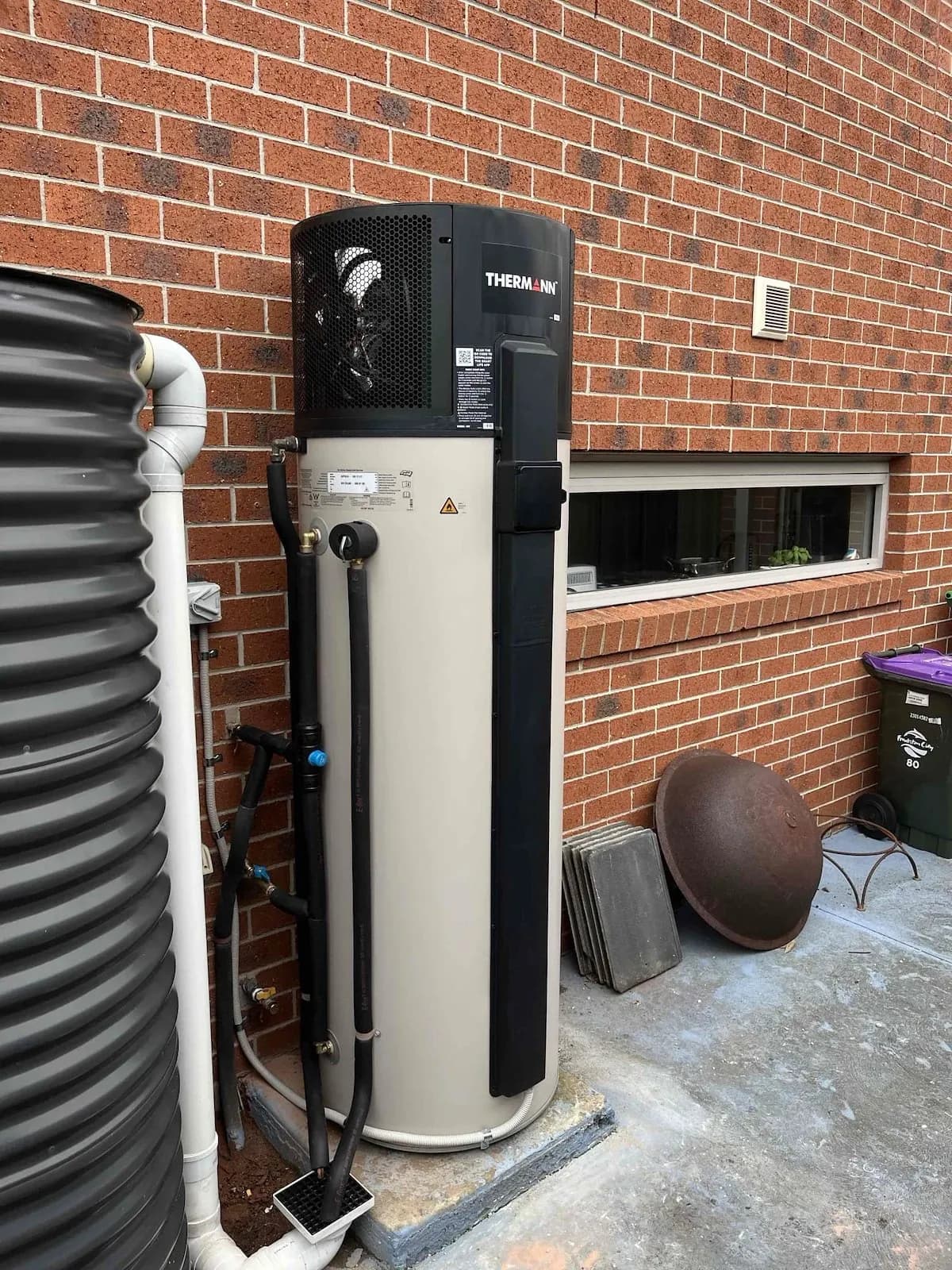 New heat pump hot water system beside a brick house