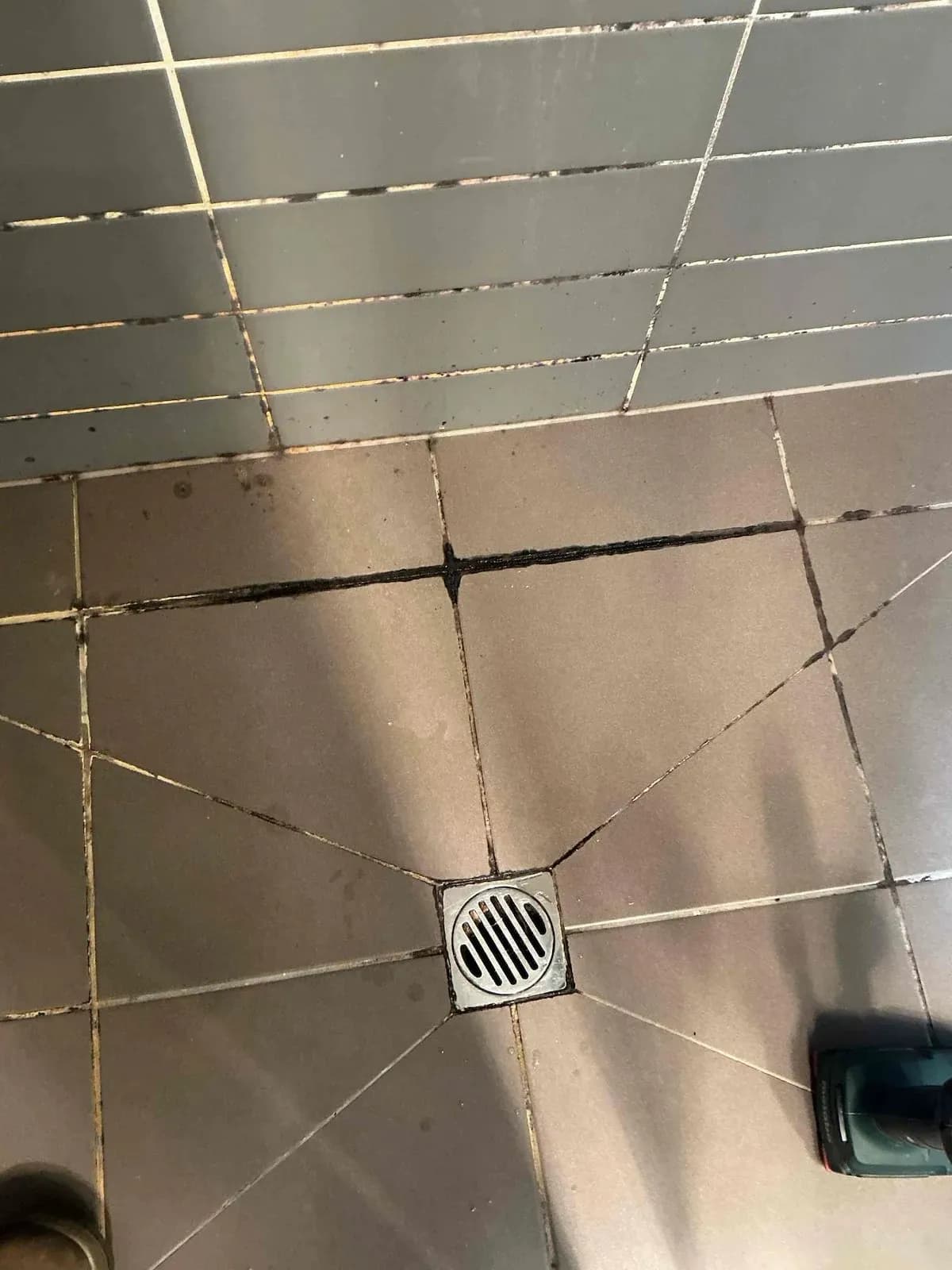 Shower floor tiles and waste with worn grout