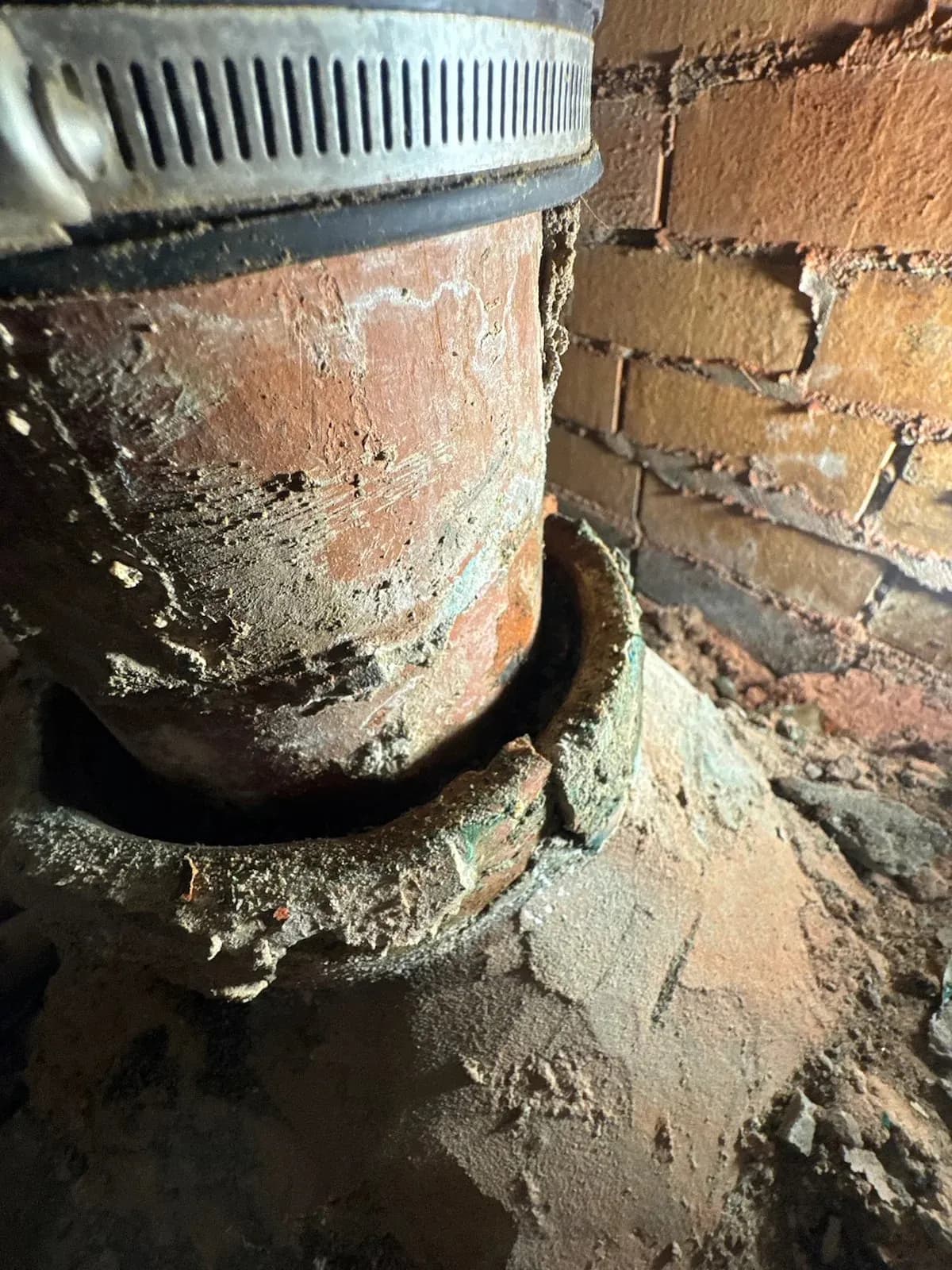 Cracked earthenware toilet pipe under the floor