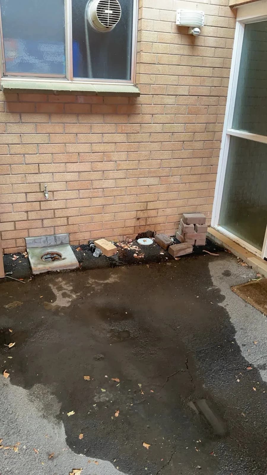 Pooled water around a blocked sewer access in a Farrer courtyard