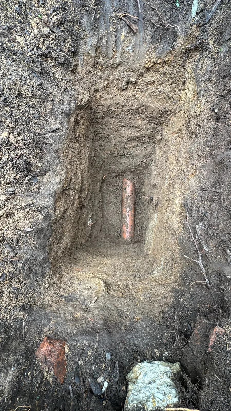 Hand-dug hole exposing the sewer line