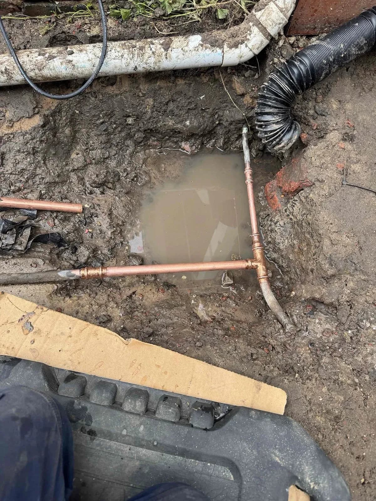 Burst water pipe exposed in a flooded hole
