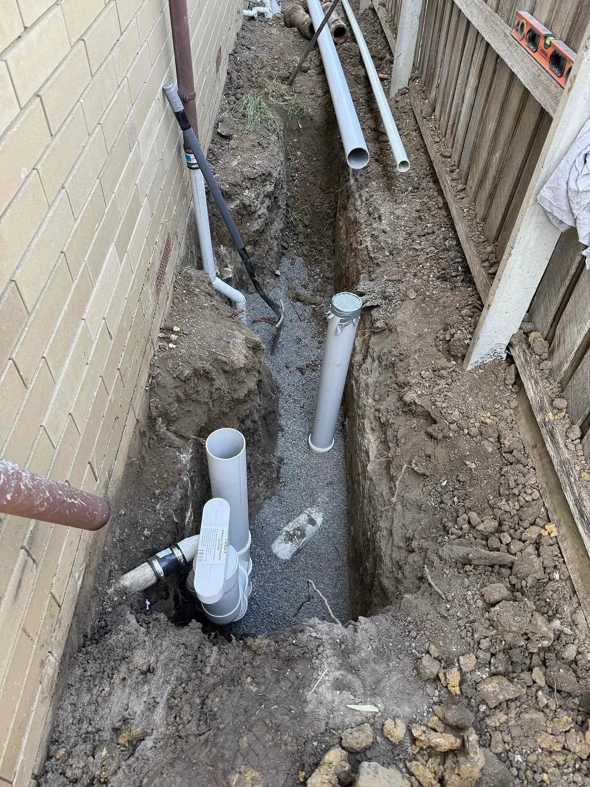 Sewer trench with new PVC fittings beside the house
