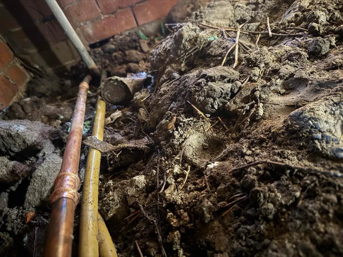 Copper water pipe exposed in the subfloor