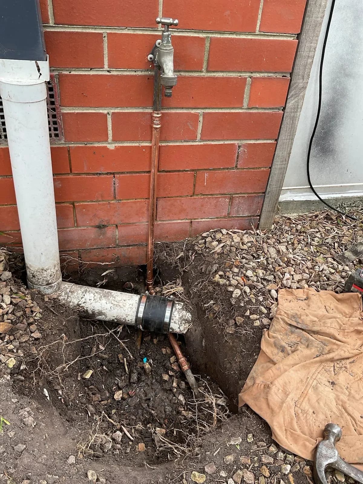 Excavated corner of a house exposing the water pipework