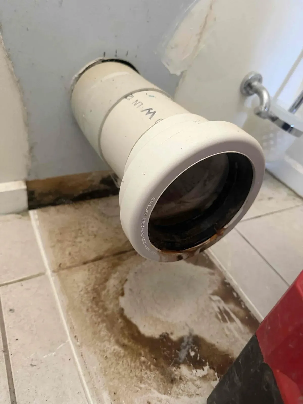 Toilet removed, showing the stained floor and pan connector