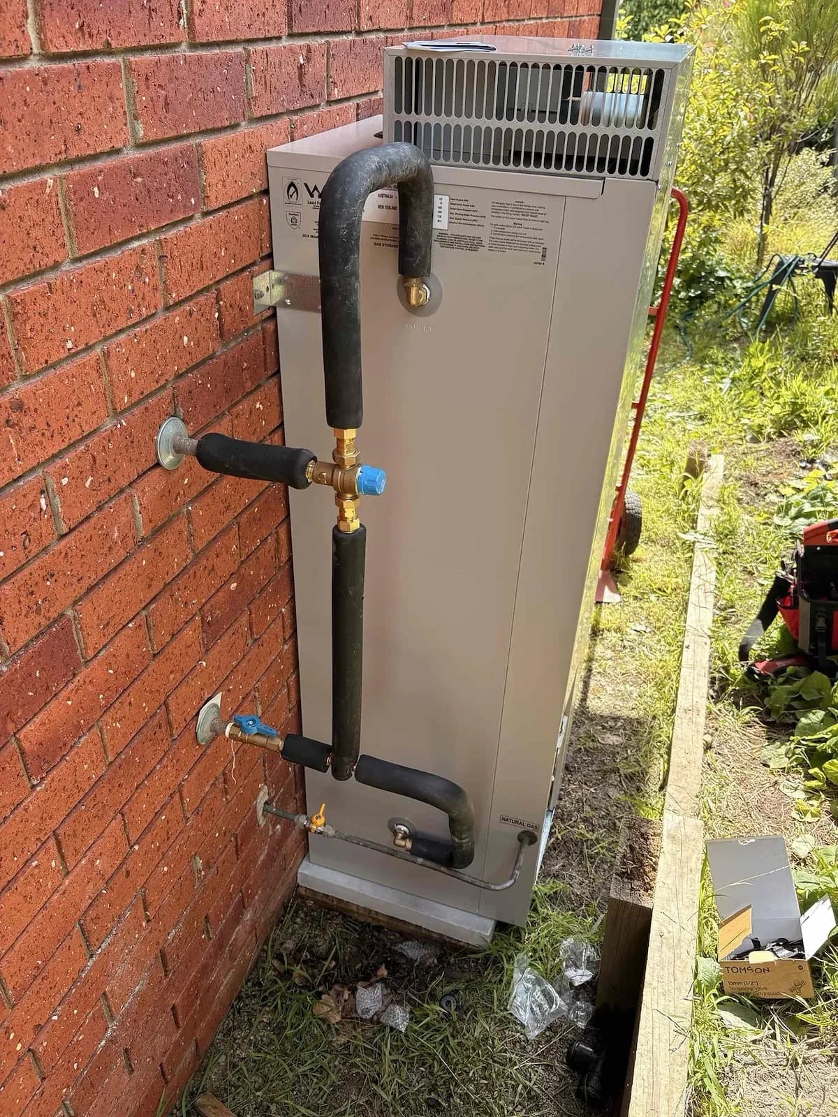 New gas storage hot water system against a brick wall