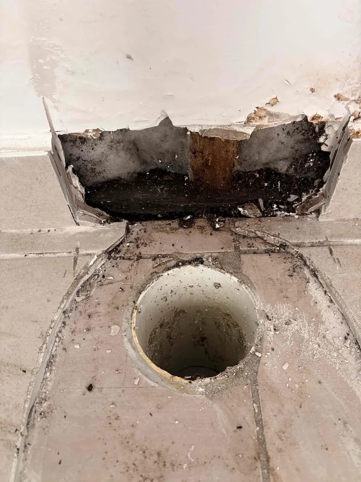 Floor and wall opened up where the shower leak caused damage