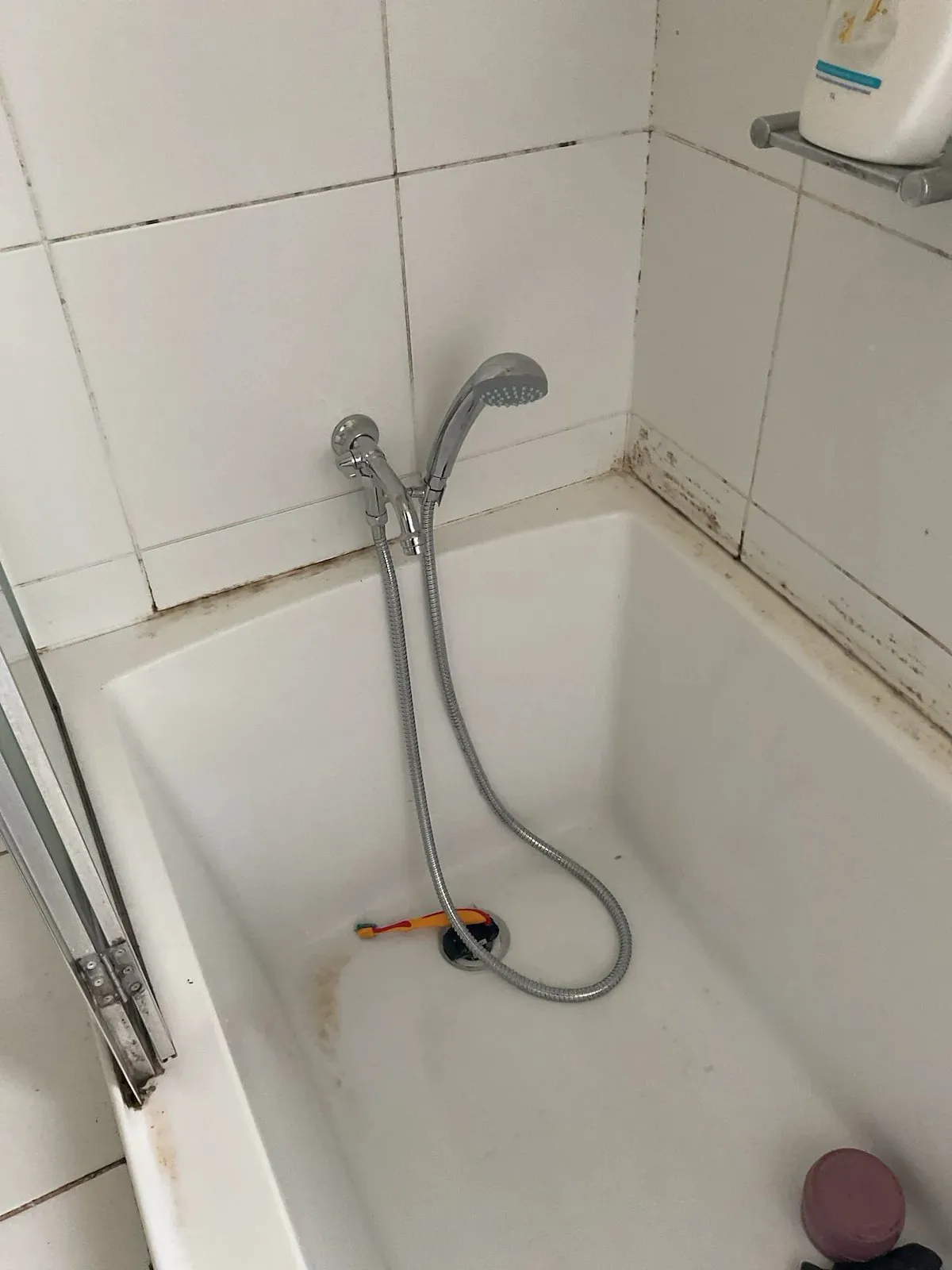 Bathtub with the old spout and hand shower before the upgrade