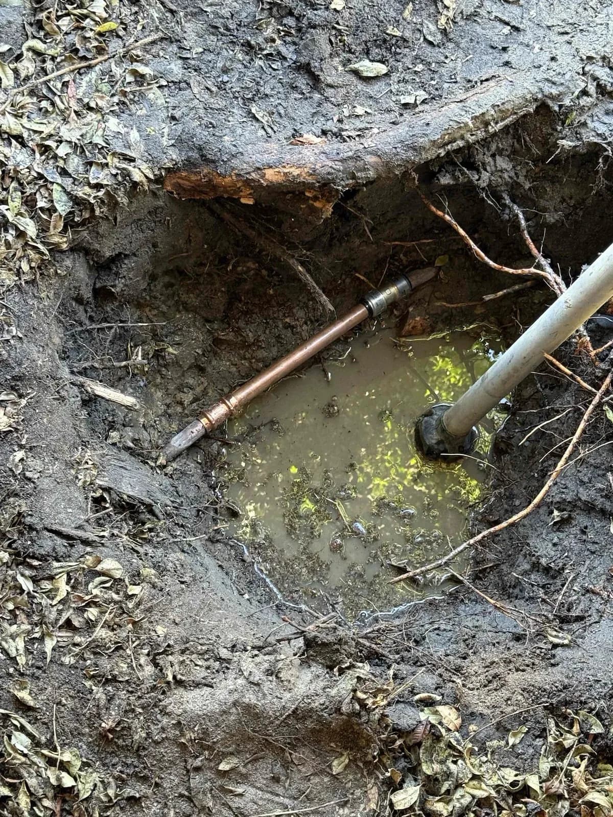 Leaking copper pipe exposed in the trench