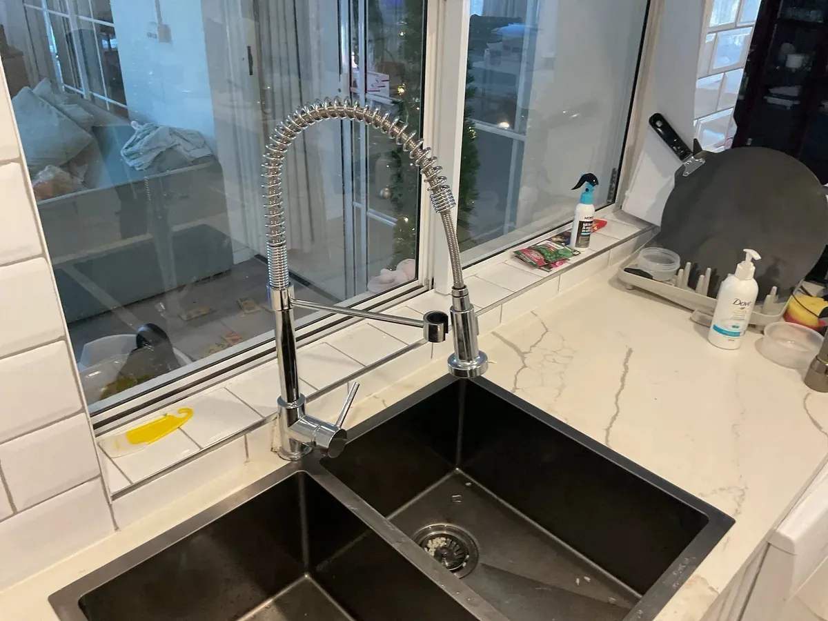 Kitchen pull-down mixer tap over a double sink
