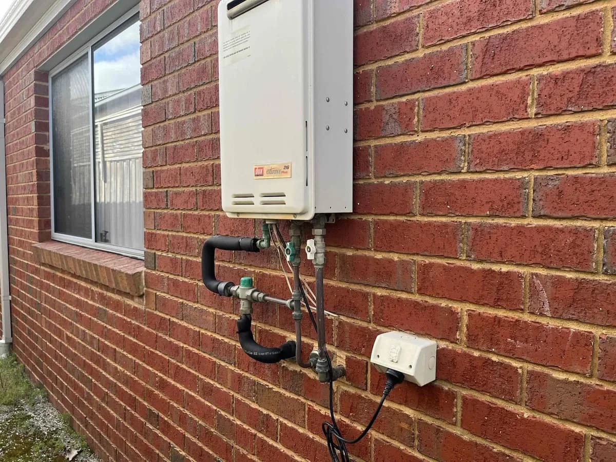 Instantaneous hot water unit on a brick wall before the repair