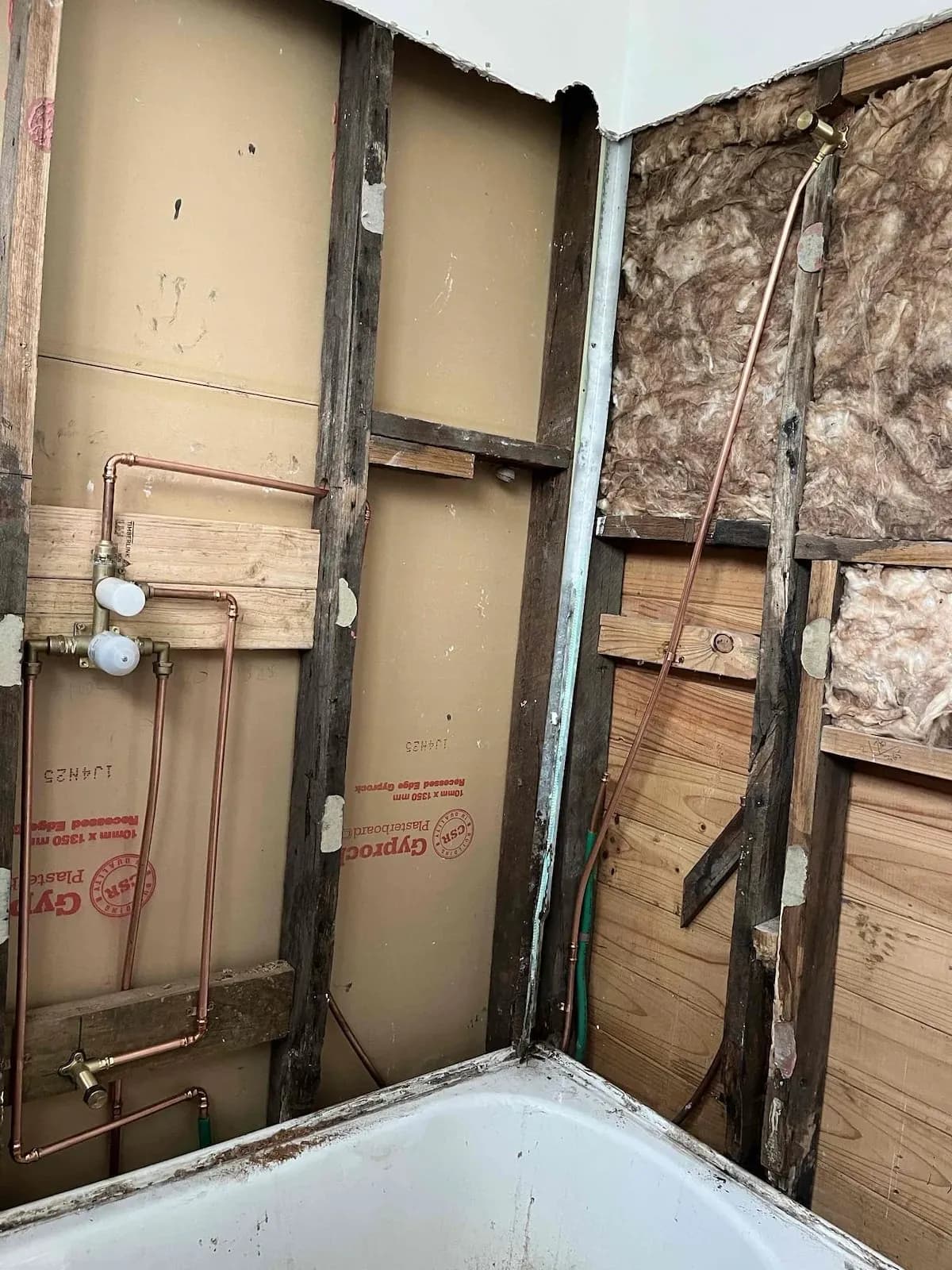 Bathroom wall stripped back to the frame showing old pipework