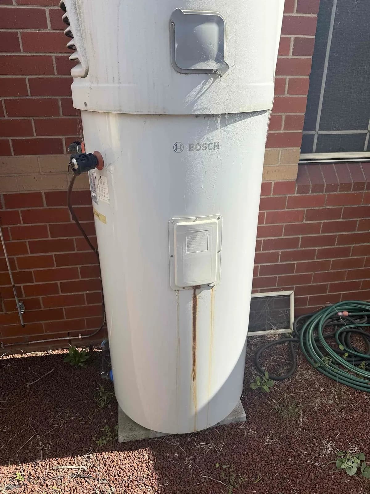 Old heat pump hot water unit with rust down the front