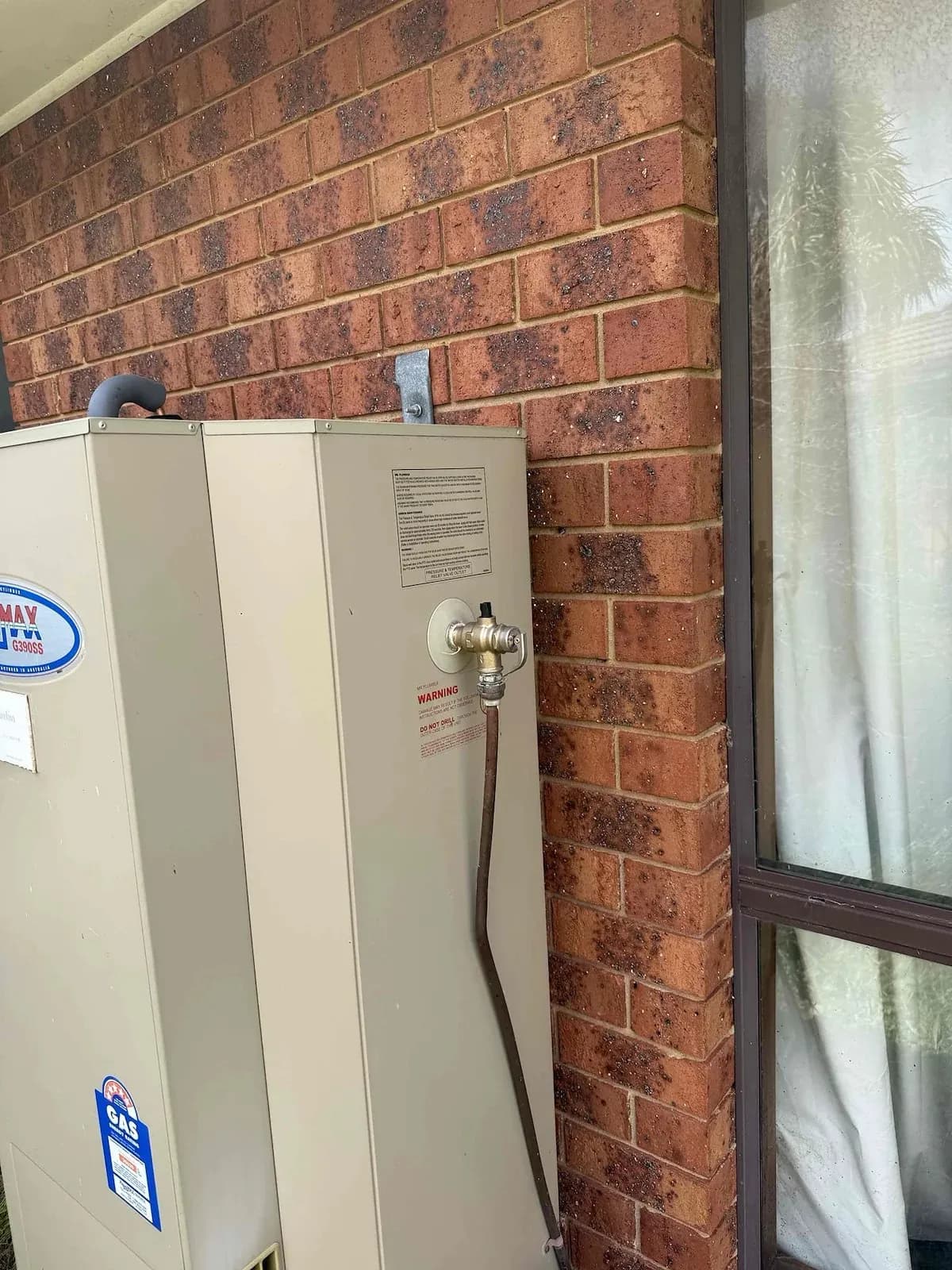 Storage hot water system with new valves on a brick wall