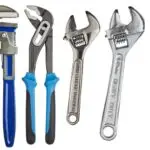 Assortment of plumbing tools including wrenches, pipe cutters, and fittings laid out on a surface, representing professional plumbing equipment used by Fix-It Right Plumbing