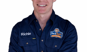 Plumber wearing a navy blue Fix-It Right Plumbing uniform, with the Fix-It Right Plumbing logo, with the name Richie embroidered on it, standing with arms crossed.